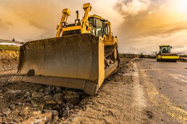 Bir yol inşaatında araziyi düzleştirmek ve düzleştirmek için kazıcı