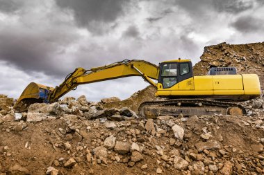 Ağır makineler açık bir madende taş ve taşı hareket ettiriyor.