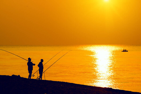 Silhouettes of fishermen  on the beach
