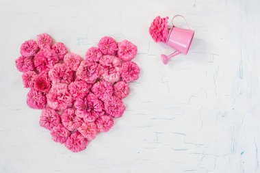 Kırık beyaz bir arka plan üzerinde kalp şeklinde gül pembe küçük çiçekler. 