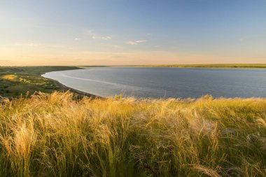 Göle bakan bir uçurumun üzerinde çim tüy çim.