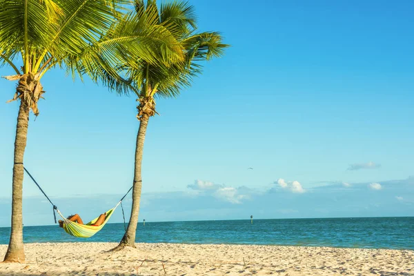 Hamak ıssız bir sahilde okyanus tarafından dinlenme bir adamla iki palmiye ağaçları arasında. — Stok fotoğraf