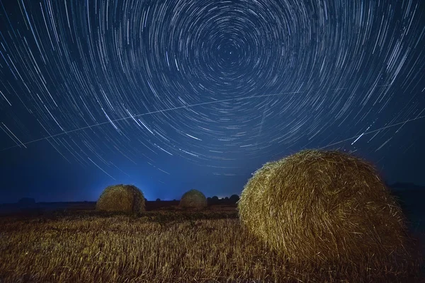 Night photo with star circles  on the field with haystacks.