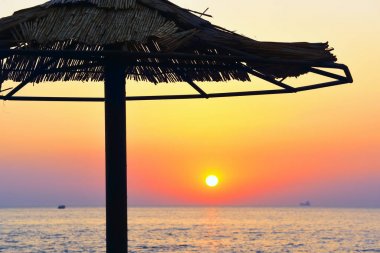 Bir saman şemsiye tente sahil üzerinde denizde şafak