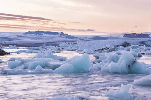 Floating on the water ice pieces and a beautiful sunset sky.