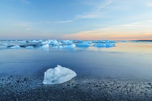 El témpano de hielo en una playa de arena negra —  Fotos de Stock