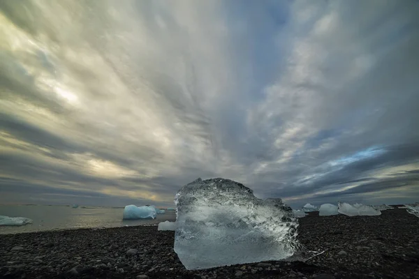 El témpano de hielo en una playa de arena negra —  Fotos de Stock