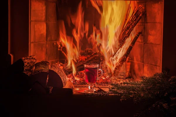 A cozy evening by the fireplace with mulled wine. Burning fire, warm cozy atmosphere, dark photo.
