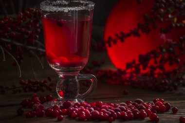 Koyu ahşap arka plan üzerinde kırmızı meyveler ile dallar arasında kızılcık suyu iç. Yumuşak seçici odak.