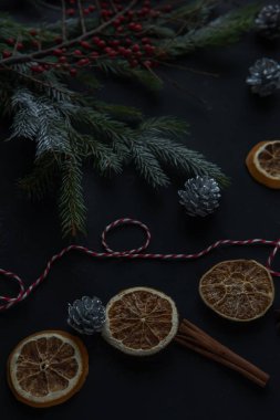 Noel süsler ve siyah bir arka plan ile ilgili ayrıntılar. Kar, kırmızı meyveler, kurutulmuş portakal ağacının dalları. Tatil için hazırlık atmosferini.