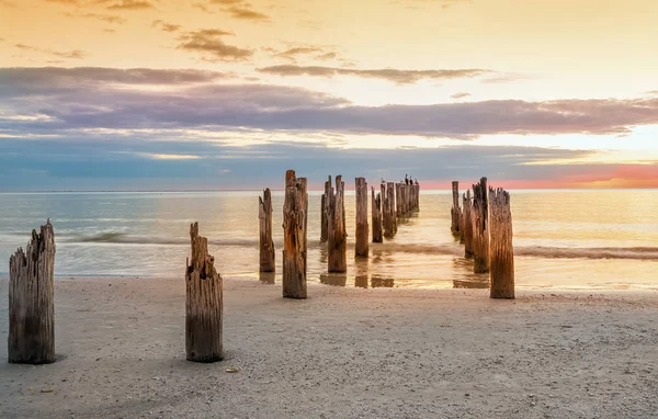 Deserted beach and and the remains of the ruined pier in  the water  . The sea is minimalist. Coast the Gulf of Mexico. Florida. USA