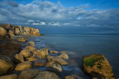 Kayalık plaj vahşi, güzel bir akşam güneş ışığı. Akşam Oda. Uzun pozlama.
