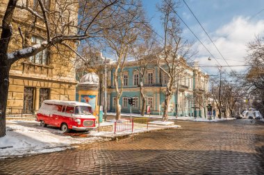 Sokağın şehrin eski kaldırım taşları ve yol kenarında üzerinde eski bir araba ile kaplıdır. Ukrayna. Odessa. Retro Araba, eski tarihi binalar. Buz gibi güneşli gün.