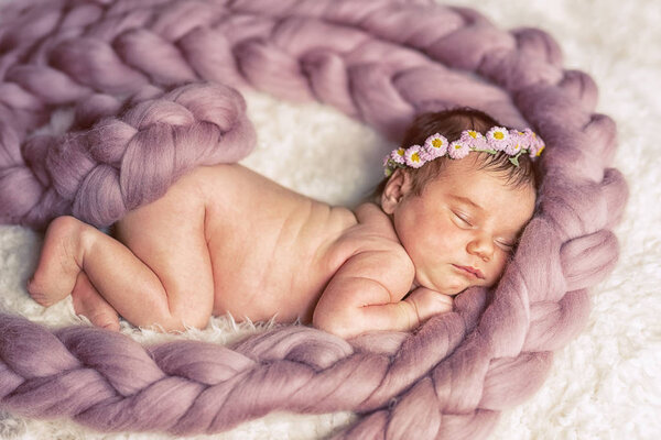 Naked Baby little girl sweetly sleeps covered with fluffy yarn.