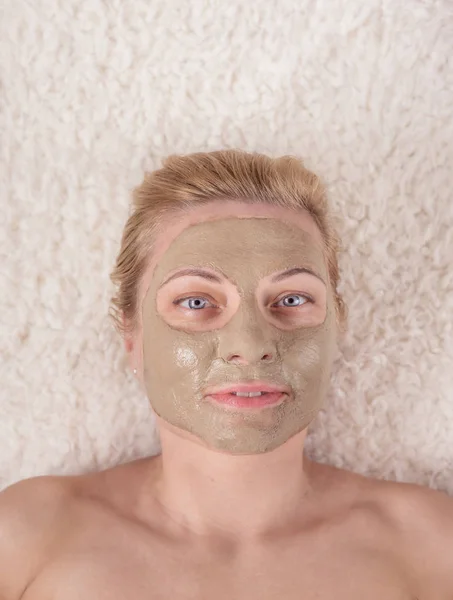 Woman\'s face in clay cosmetic mask closeup.