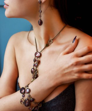 Farklı dekoratif mücevherlerle süslenmiş bir kızın elleri ve vücudu. Bileklik yakın planda olsun. Boynunda taşlar olan bir kolye. Şık aksesuarlar.