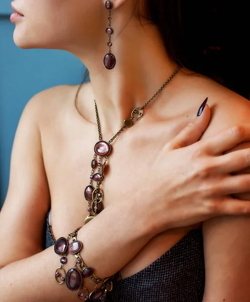 Farklı dekoratif mücevherlerle süslenmiş bir kızın elleri ve vücudu. Bileklik yakın planda olsun. Boynunda taşlar olan bir kolye. Şık aksesuarlar.