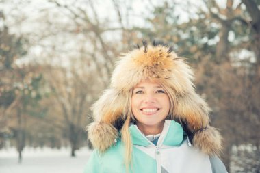 Kış parkında kürk şapkalı neşeli bir kadın. Rötuş yapmadan gerçek bir kadının doğal görünüşü. Klasik stil.