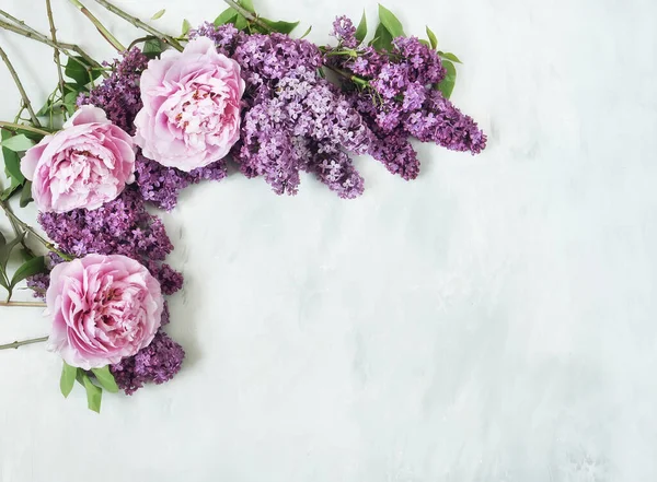 Flowers composition. Branches of lilac flowers of lilac and delicate pink peonies on a gray background. Valentines day, mothers day, womens day concept. Flat lay, top view, copy space