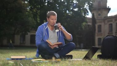 Mutlu genç öğrenci parkta bir kitap okuma