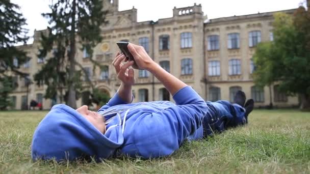 Jonge mannelijke student browsen op smartphone — Stockvideo