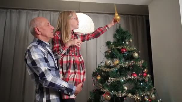 Sweet little girl adjusting Christmas tree top. — Stock video