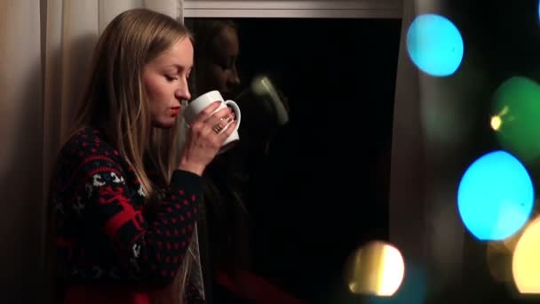 Beautiful woman drinking coffee on Xmas Eve — Stockvideo