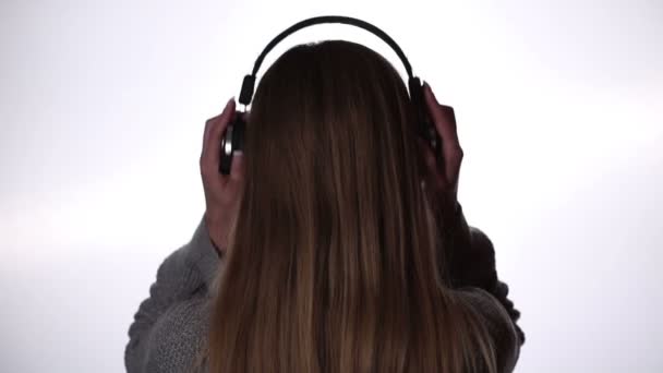 Вид сзади женщины, слушающей музыку в наушниках — стоковое видео