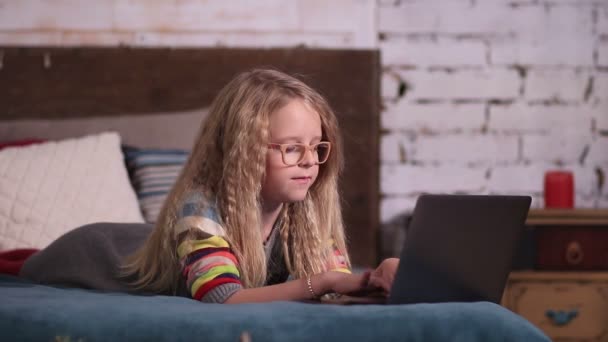 Linda niña jugando con el ordenador portátil en la cama — Vídeos de Stock