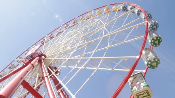 Ярко окрашенное колесо обозрения против голубого неба — стоковое видео