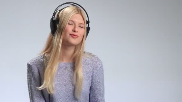 Эмоциональная девушка в наушниках, слушающая музыку — стоковое видео