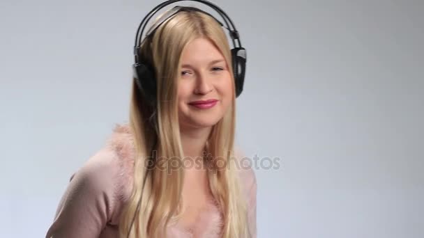 Игривая женщина с наушниками, слушающая музыку — стоковое видео