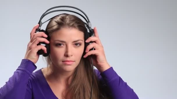 Mujer bonita alegre escuchando música en auriculares — Vídeo de stock