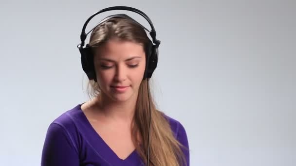 Экспрессивная девушка в наушниках наслаждается музыкой — стоковое видео
