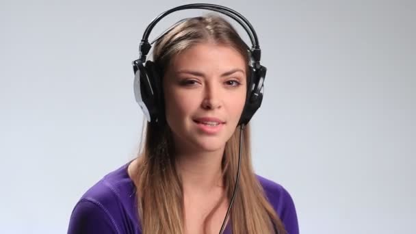 Linda chica sonriente escuchando música en los auriculares — Vídeos de Stock