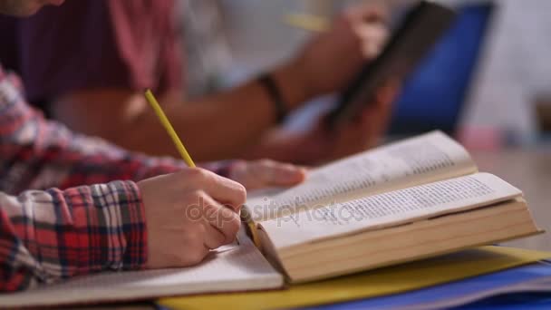 Estudiantes manos con libros que escriben a cuadernos — Vídeos de Stock