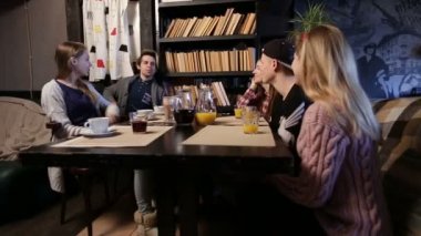 Grup genç arkadaşlar kahve dükkanında dışarı asılı.