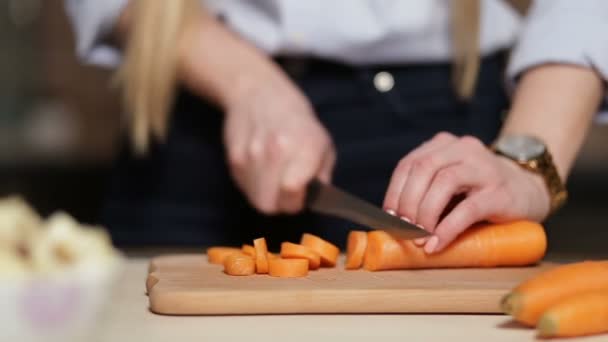 Dames hand snijden wortel aan boord met mes — Stockvideo