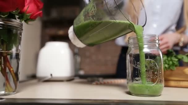 Pouring fresh green smoothie from blender into jar — Stock Video