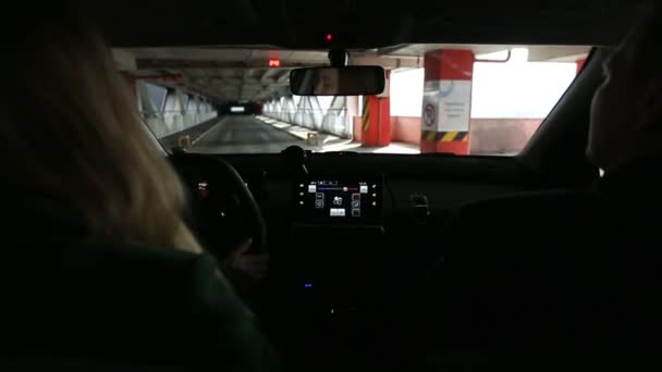 Mujer conduciendo coche dentro de la estructura de estacionamiento cubierto — Vídeo de stock