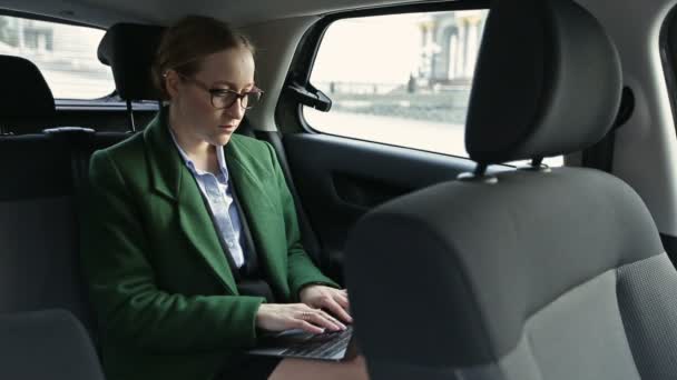 Серьезная деловая женщина, работающая в машине на ноутбуке — стоковое видео