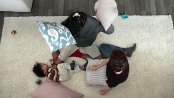 Vista superior de la almohada de la familia feliz luchando en la alfombra — Vídeos de Stock