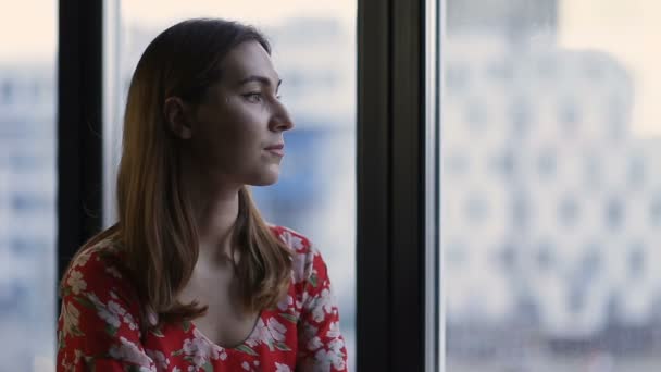 Профиль женщины, выглядывающей в окно — стоковое видео
