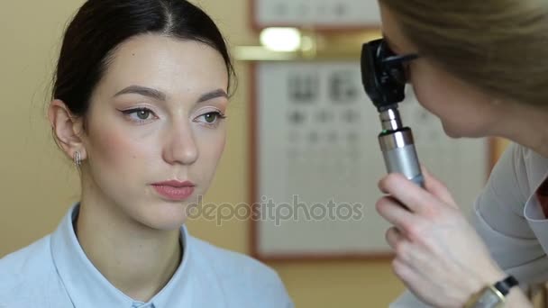 Optometrist die zijn patiënt ogen controleren met retinoscope — Stockvideo