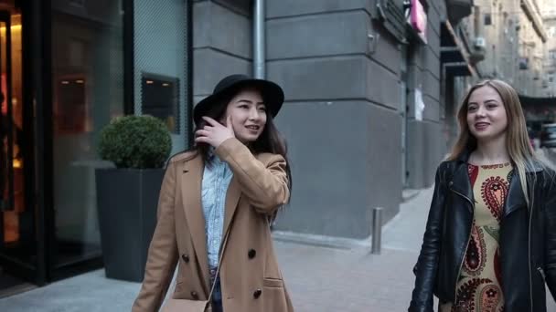 Duas jovens mulheres com sacos de compras andando na cidade — Vídeo de Stock