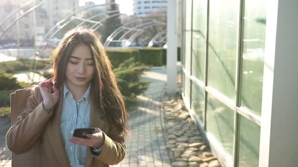 智能手机户外微笑亚洲女人用发短信 — 图库视频影像