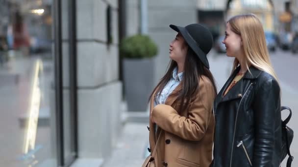 Duas jovens mulheres olhando para a janela da loja de roupas — Vídeo de Stock