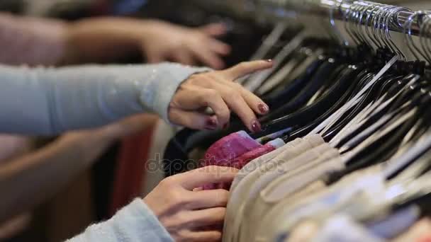 Female hands selecting colorful clothes on hangers — Stock Video