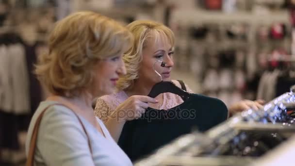 Starszych kobiet, wybierając strój podczas zakupów w sklepie — Wideo stockowe