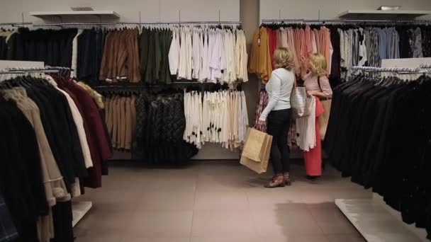 Mooie shopaholic vrouwen kopen van kleren in opslag — Stockvideo